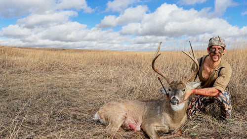 Hunter kneeling beside a harvested deer in Southeast Iowa